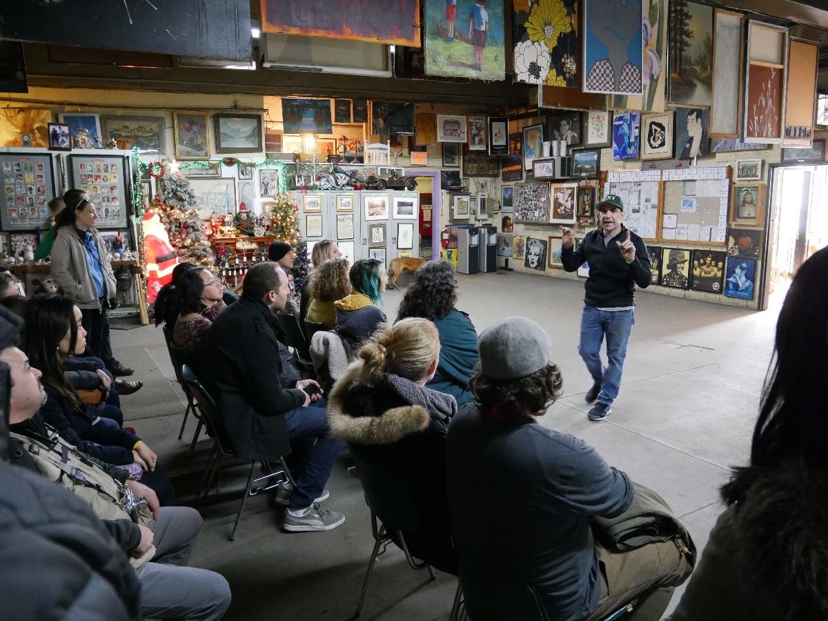 Nelson Molina speaking to a group of people within the room that has housed his collection for the past 30 years.
