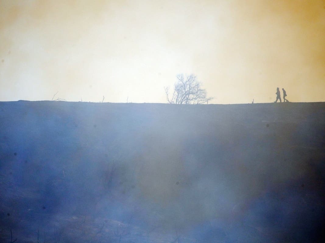 Firefighters walk on top of a burned down canyon caused by the Getty fire on Mandeville Canyon on Monday in Los Angeles.