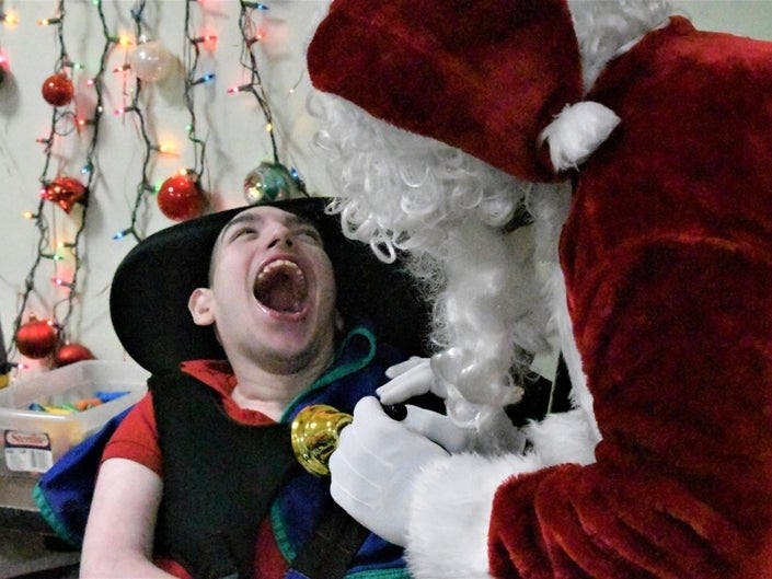 James Tracey (left) has been at Baby House since 2005. His smile brightened Santa's day. (Photo by Paul Sciccitano)