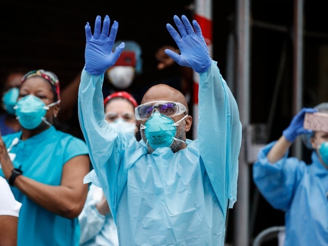 Medical workers cheer and acknowledge pedestrians and New York firefighters who gathered to applaud them at 7 p.m. outside Brooklyn Hospital Center.