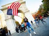 A woman waves the American flag near the arch in Washington Square Park.