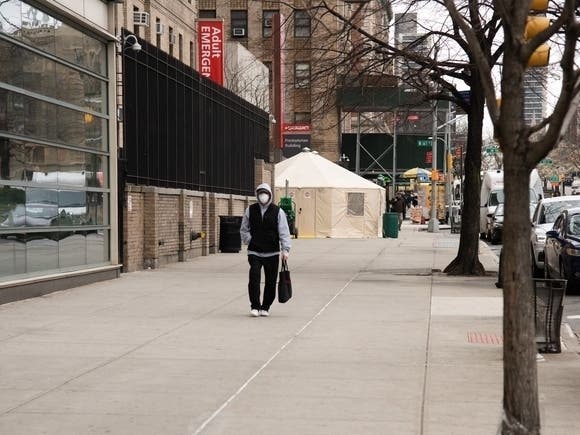 An image of a man wearing a mask walking in Washington Heights.