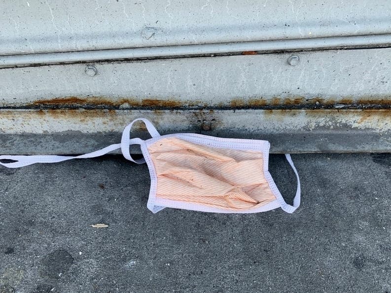 An image of a broken, discarded mask on a street in Washington Heights.