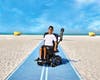 Surf Style model Andrew Brettner, who has cerebral palsy and uses a power wheelchair, poses on a mobility mat on a beach in Treasure Island.