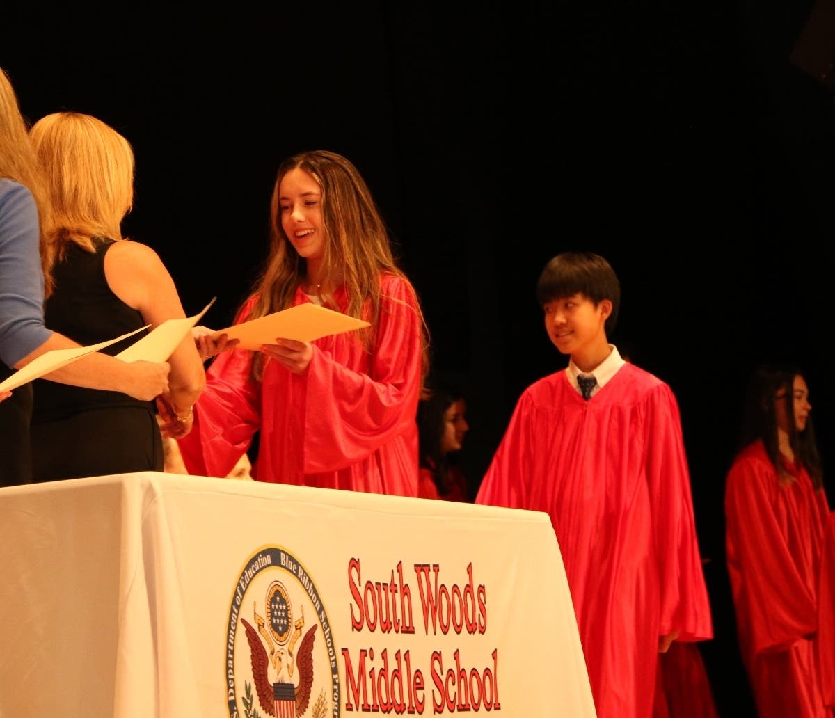 Eighth grade graduates receive their certificates from South Woods Middle School Principal Michelle Burget.