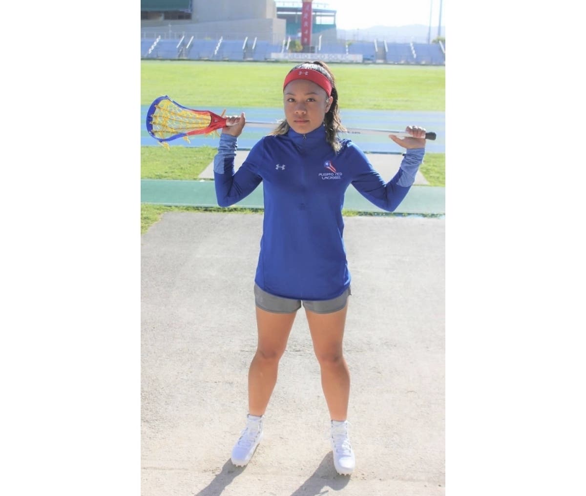Northport's Jolie Benabe, who has represented Puerto Rico in lacrosse, stands with her lacrosse stick behind her back.