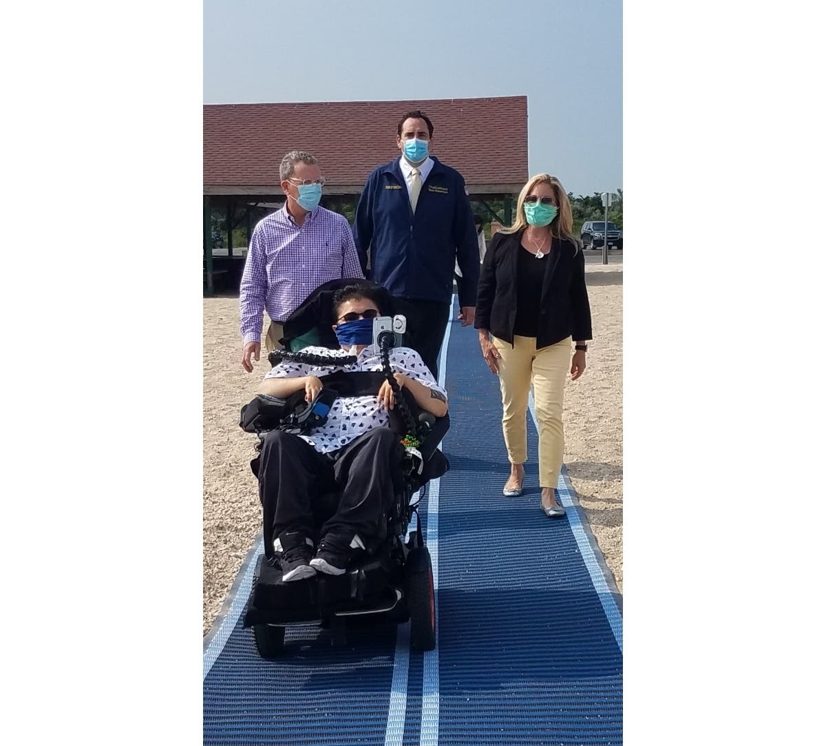 L-R: Councilman Mark Cuthbertson; Supervisor Chad A. Lupinacci; Councilwoman Joan Cergol follow Dylan Thompson on the Mobi Mat at Crab Meadow Beach.