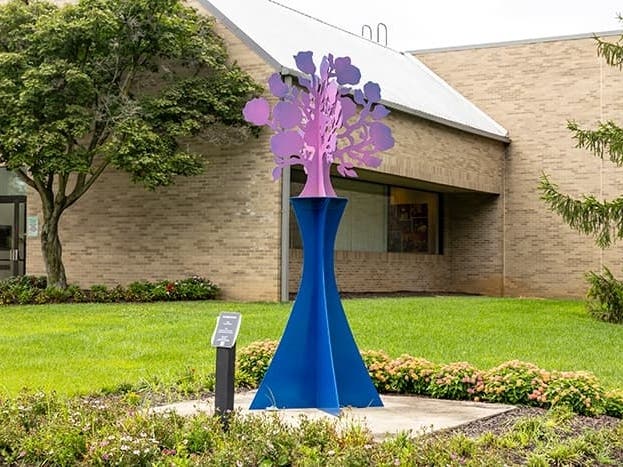 Made from powder-coated aluminum, the 9-foot tall sculpture stands on a concrete base. It will be on display outside the department of education building through July 2024. 