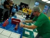 Ted Swartwood, regional manager for New York and New Jersey for the Outreach Program, showed volunteers how to press seal a plastic bag containing food.