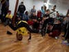 A bboy from 6 Steps Before the Lord performed a power move in the intermediate level dance battle. His opponent to the right in the black shirt raised two fingers gesturing his opponent repeated a move.