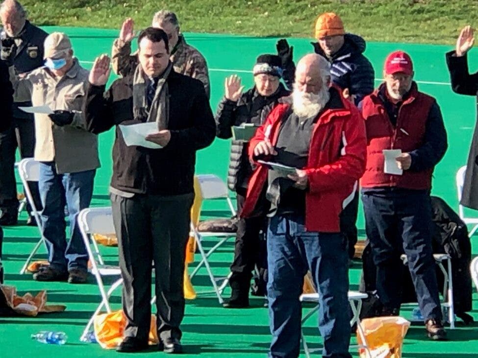 Some of the estimated 80 House members who didn't wear a face mask are pictured being sworn in on Organization Day outside at UNH on Dec. 2.