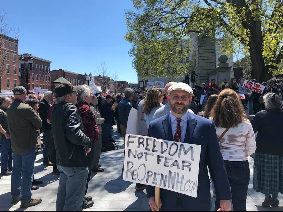 Andrew Manuse is pictured holding a sign in the foreground at a rally last year in front of the State House in Concord.