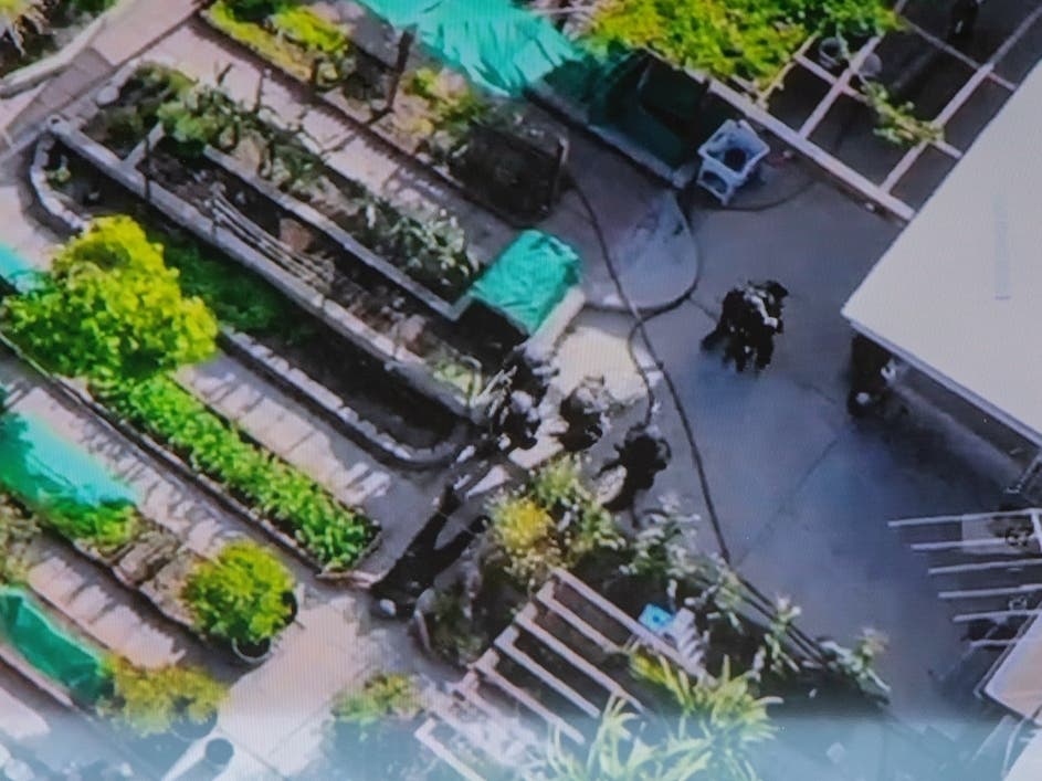Officers watch a drone feed of the raid as it goes down from outside the mobile command center.

