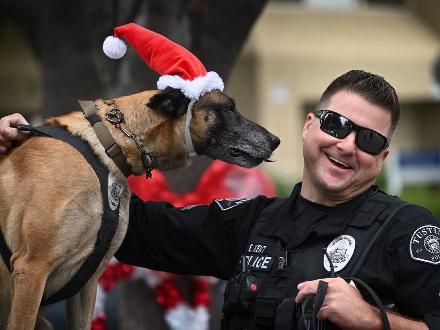 Tustin Police Officer Eric Kent smiles after getting his K9 partner, Roky, a Belgian Malinois, ready to greet kids for Tustin Police Department’s annual Santa Cop event.