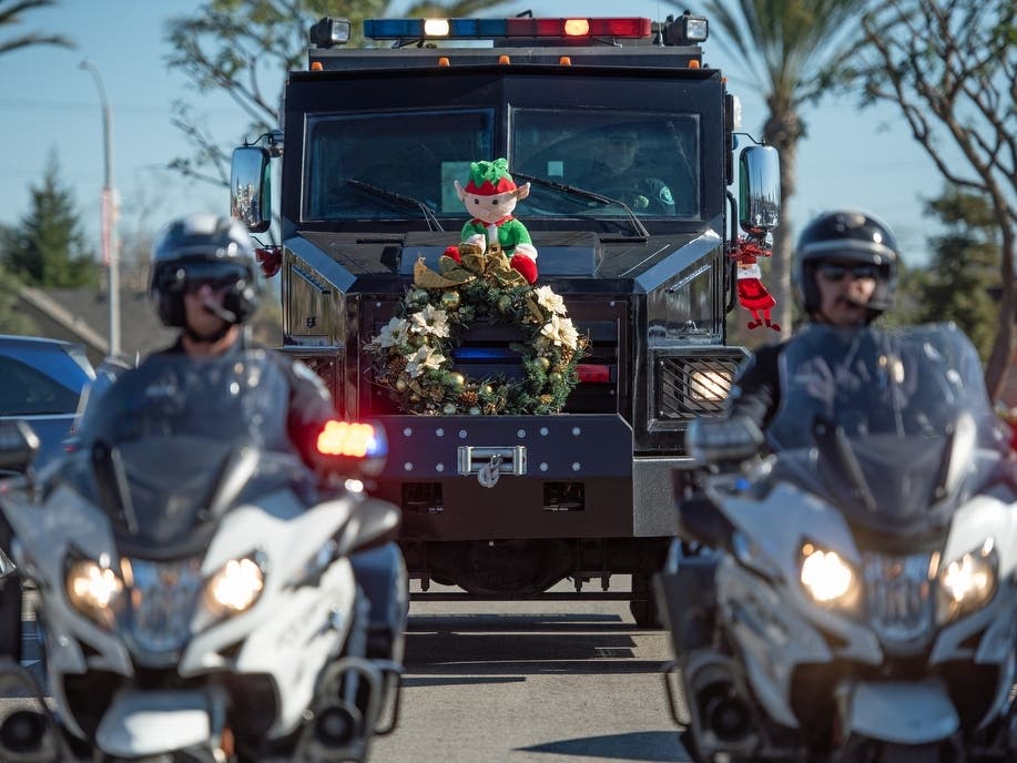 
Motorcycle officers escort the Santa Ana Police Department’s SWAT vehicle as it arrives, stuffed with donated toys, to make a delivery at the Spark of Love Toy Drive at Santa Ana College on Friday, December 17.