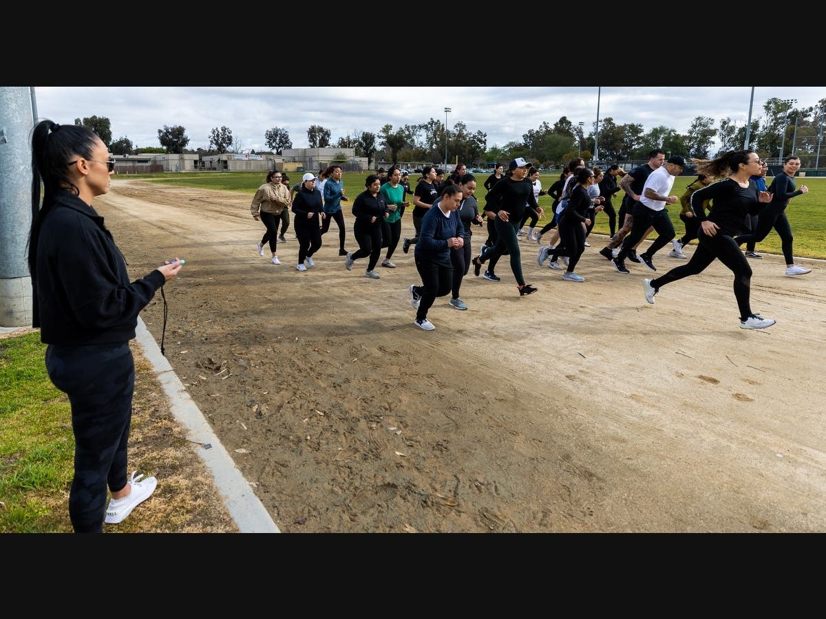 Santa Ana Police Officer Joanna Hatzefstratiou starts the clock as participants take off for the 1.5 mile run during the Female Training Class at Centennial Park.