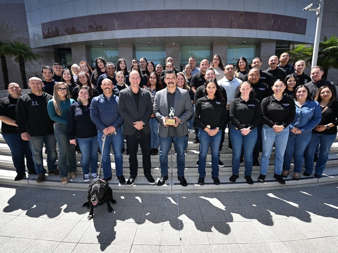 The Santa Ana Police Department gathers on the steps of police headquarters with Shadow, their black lab, to raise awareness of Denim Day and Sexual Assault Awareness Month.