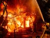 A firefighter sprays water on a burning home as the Kincade Fire burns through the Jimtown community of unincorporated Sonoma County, Calif., on Thursday, Oct. 24, 2019.
