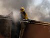 A structure firefighter works on the roof of a building during the Tick fire in the Santa Clarita area of Los Angeles, Calif. on Thursday, Oct. 24, 2019