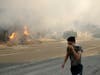 Brando Mani covers his face from the smoke created by a wildfire as he walks along highway 14 Thursday, Oct. 24, 2019, in Santa Clarita, Calif.