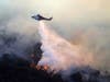 A helicopter drops water as the Getty fire burns on Mandeville Canyon on Monday in Los Angeles.