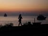 A woman walks along the waterfront Monday, Oct. 28, 2019, in Sausalito, Calif., as smoke from wildfires blankets the San Francisco skyline in the background.