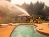 Firefighters spray water on a spot fire at a home during the Kincade Fire on Vinecrest Road in Windsor, Calif., on Sunday, Oct. 27, 2019.