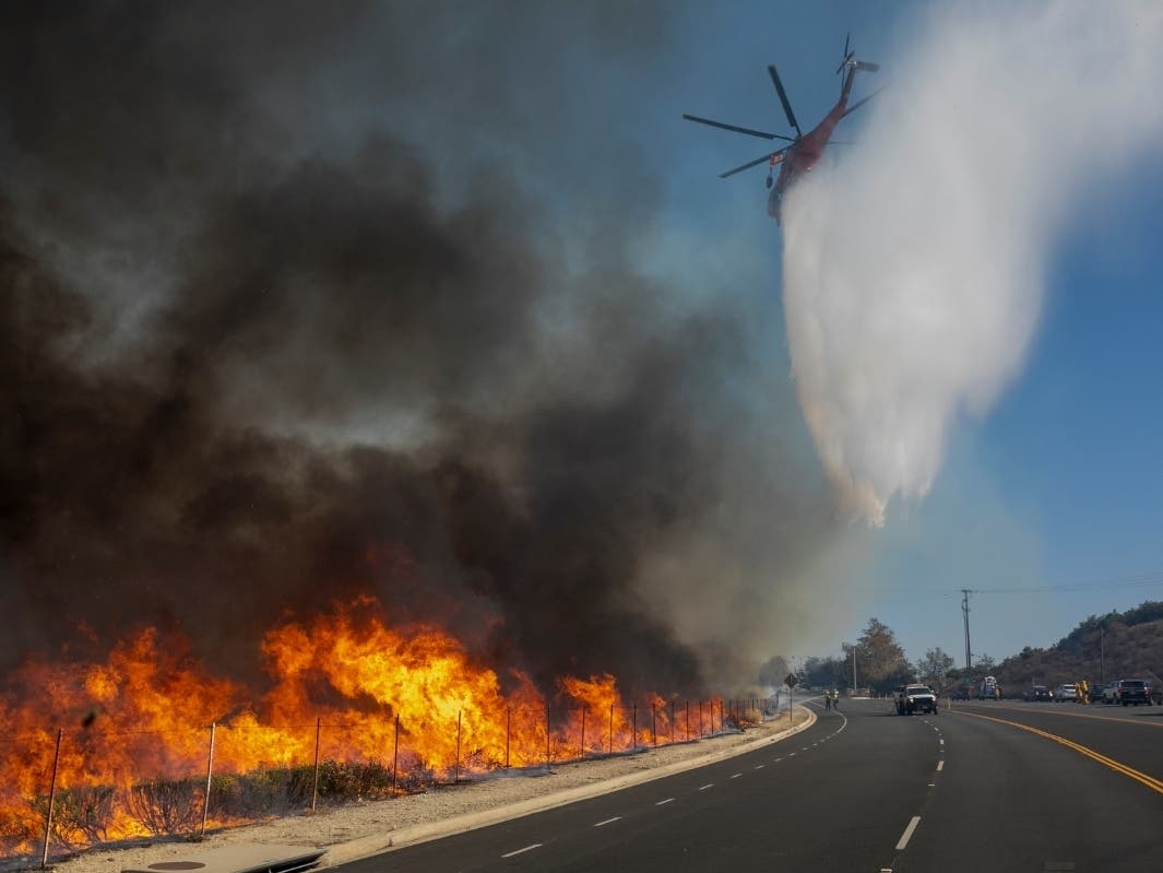 A firefighting helicopter makes a water drop over the Easy Fire on October 30, 2019 near Simi Valley, California.