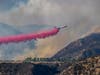 A plane drops fire retardant over a home as the out-of-control Apple fire burns around it during the coronavirus pandemic on August 1, 2020 in Cherry Valley, California.