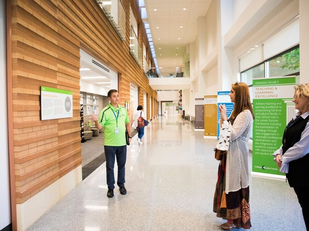 From left: David Husemoller, CLC sustainability manager, points to one of the new Living Lab Trail signs inside the Science & Engineering Building.
