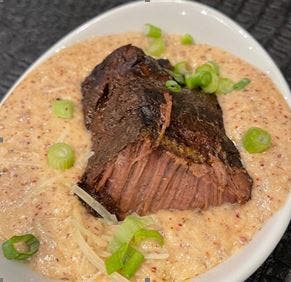 BLACK ANGUS SHORT RIBS & RED GRITS, $30 Creamy purple and red grits cooked in a cheese and butter sauce topped with sliced black angus short ribs.