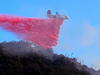 A Cal Fire plane drops fire retardant near a home on the east side of Painted Cave Road.
