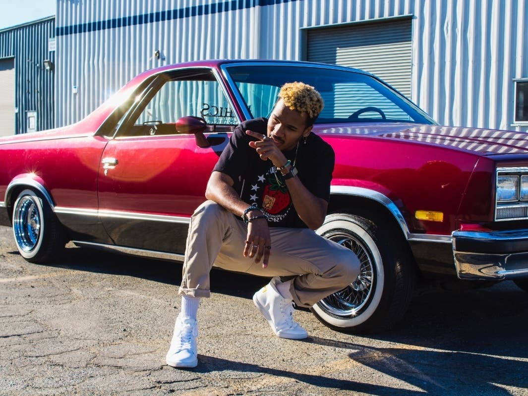 Kabwasa reps Watsonville strawberries on his t-shirt, in a photo taken from the set for song "Watson."