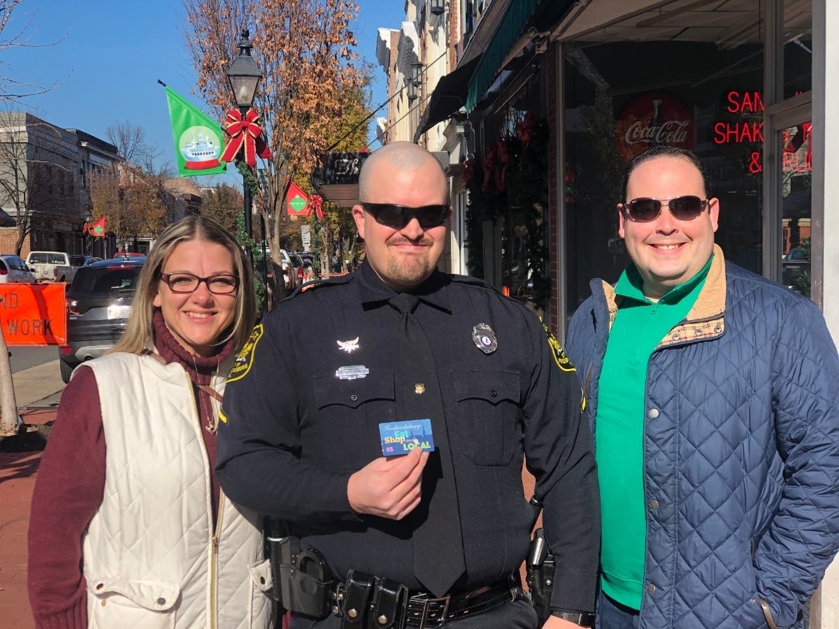 Fredericksburg police officer displays Downtown Gift card.