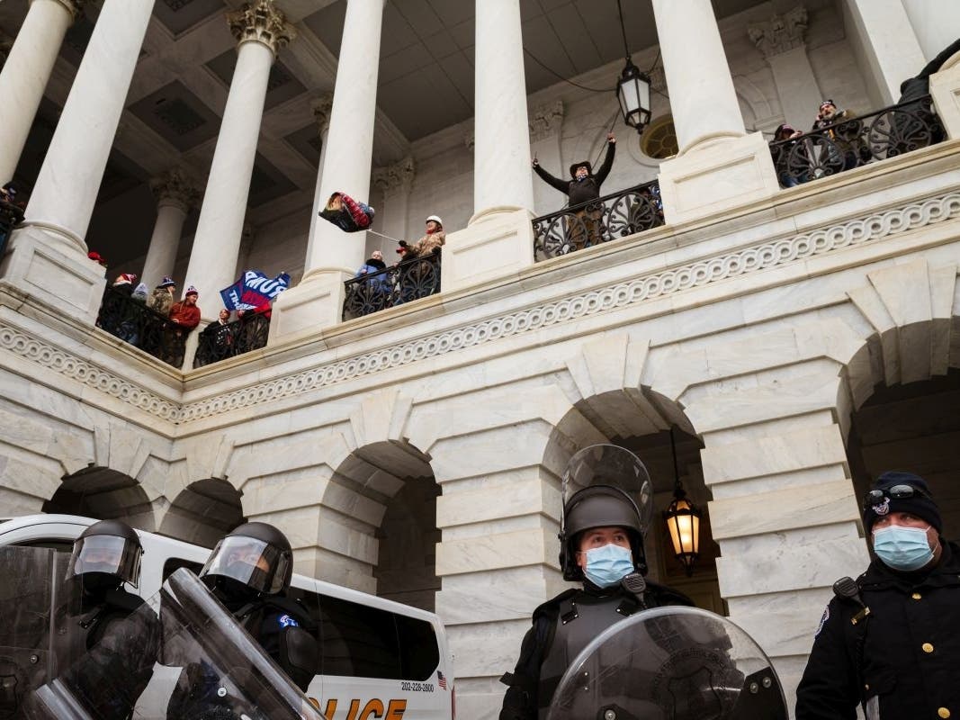 A group of pro-Trump rioters wave flags from a platform above a group of Capitol Police after storming the Capitol Building on Jan. 6.