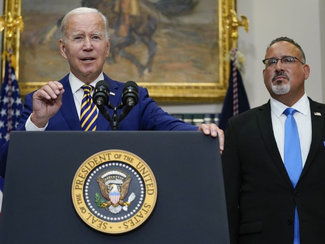 President Joe Biden speaks about student loan debt forgiveness in the Roosevelt Room of the White House on Wednesday. U.S. Education Secretary Miguel Cardona listens at right.