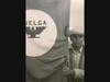 Black and white image of man holding a tall cloth banner that says "Huelga" with the image of a bird with outstretched wings.