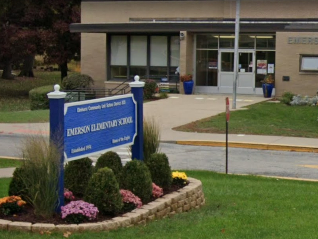 Seven kindergarteners at Emerson Elementary School were seen sitting on blankets on the sidewalk in front of the school. They were eating a snack.