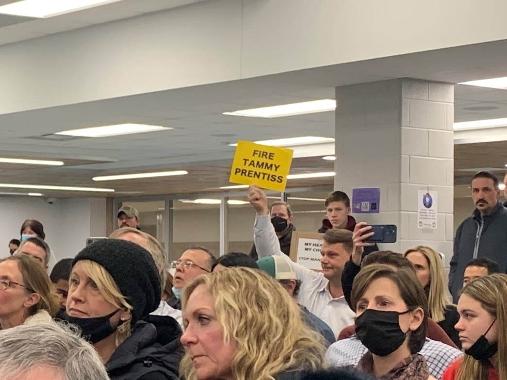 A man holds a "Fire Tammy Prentiss" sign during Thursday's meeting of the Hinsdale High School District 86 board. It was referring to the superintendent. Others displayed the same sign.