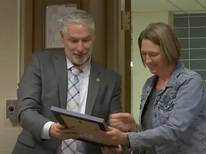 Julie Swinehart, a former member of the Lyons Township High School board, accepts a plaque from Superintendent Brian Waterman on Tuesday. They appear in a screenshot of the school's video of a board meeting. 