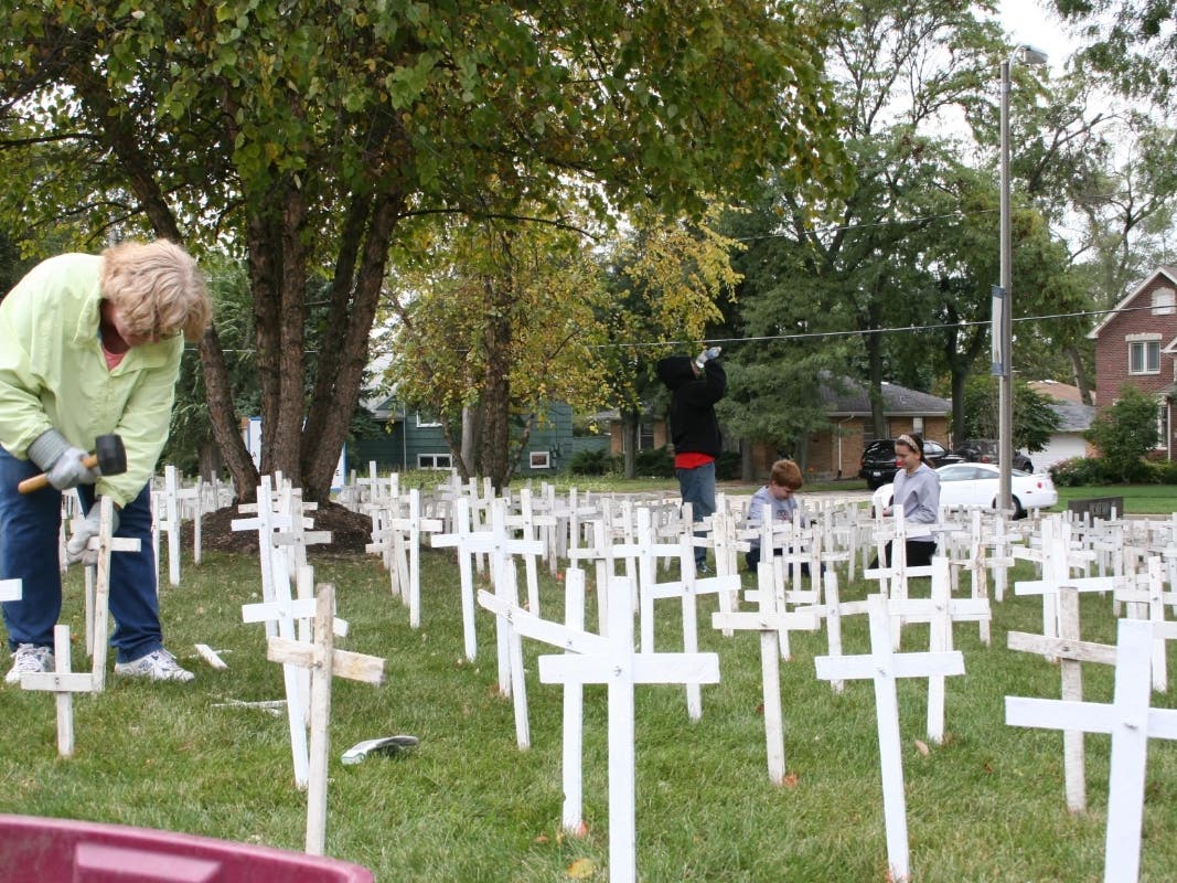 A woman puts up pro-life crosses in 2010 on the lawn at Visitation Catholic Church in Elmhurst. This year, the church says it won't put them up.