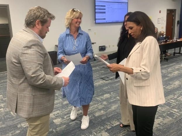 Courtenae Trautmann (in blue), an Elmhurst School District 20 board member, swears in colleagues at a meeting last April. From left are Brian Bresnahan, Athena Arvanitis (obscured) and Nicole Slowinski.