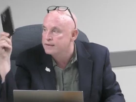 Darien Alderman Joe Kenny points to his cellphone while making the case that he supports a police contract to buy drivers' location data to track speeding problems. 