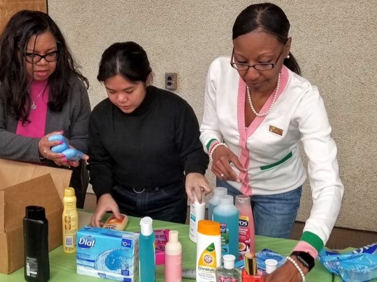 From left, Alpha Kappa Alpha Sorority, Inc. Psi Epsilon Omega Chapter President Benita Swindell, high school student volunteer Kristiana Mateo, and vice president Cassandra Jones sort items at MLK day of service in Greenbelt.