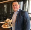 Adam Christian, general manager of the new The Capital Burger in Reston, holds a French-onion style burger that's the inspiration for his restaurant's name.