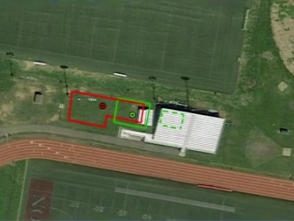 The original plan called for a 2,590 square foot, fenced-off compound located in the open space near the visitors bleachers. The revised  plan (green) shifted the smaller compound partially under the bleachers.