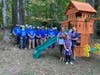 Josh and Rachel Snell pose with their daughters Em and Sonja along with the volunteers who installed the new playset at their Reston home.