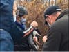 Volunteer wildlife rescuers Billy Rios and Peshwaz Faizulla cut fishing line off the wing and legs of a Great Blue Heron at Kingstowne Lake.