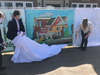 From left, Mayor David Meyer, IDI Managing Director Enrico Cecchi, and Mrs. PJ Naber reveal the mural created by Kaia Collins highlighting the city's history 
