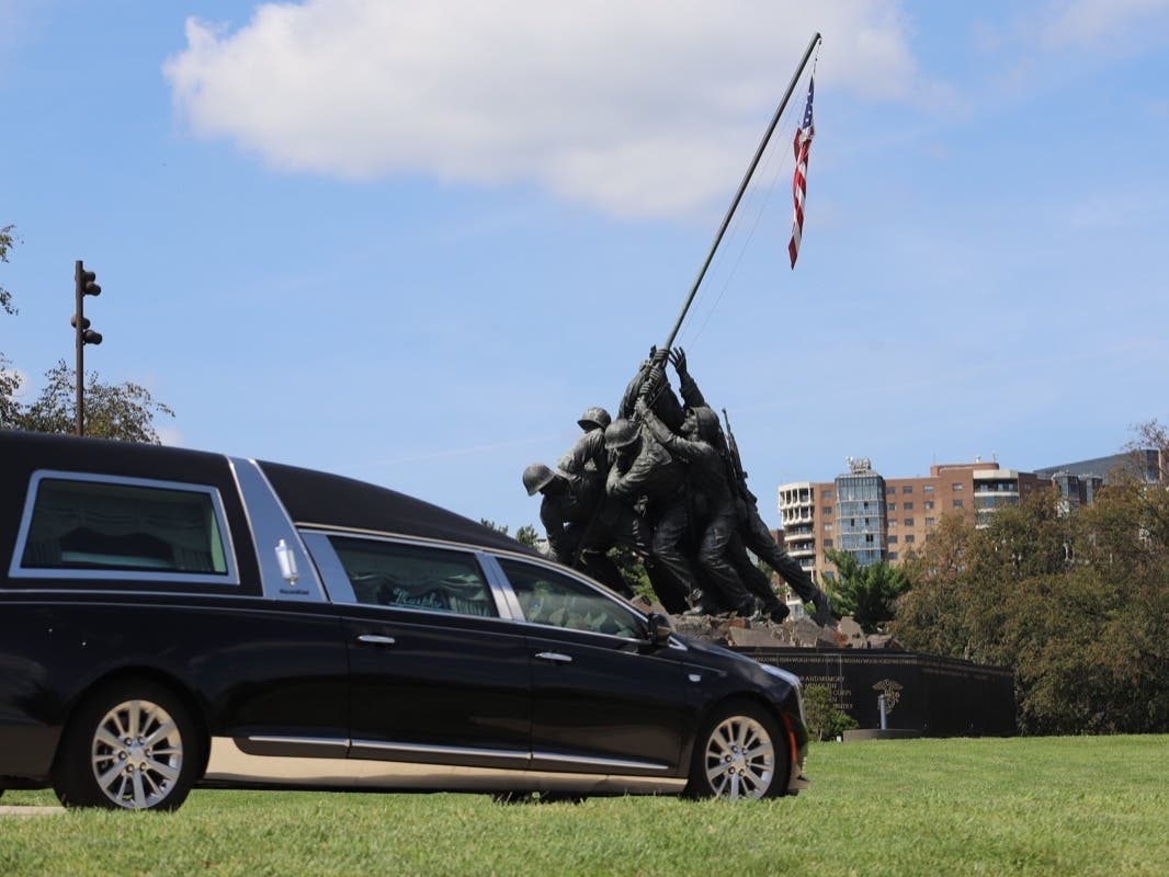 A funeral procession carrying the body of a U.S. Marine killed in the Aug. 26 suicide bombing in Kabul drives past the Iwo Jima Memorial in Arlington, Virginia on Monday.